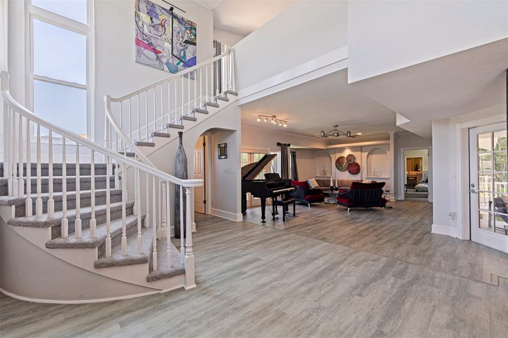 A foyer with a curved staircase, wood-look flooring, and an open view into a living area — 1156 2ND AVENUE S, TIERRA VERDE, FL