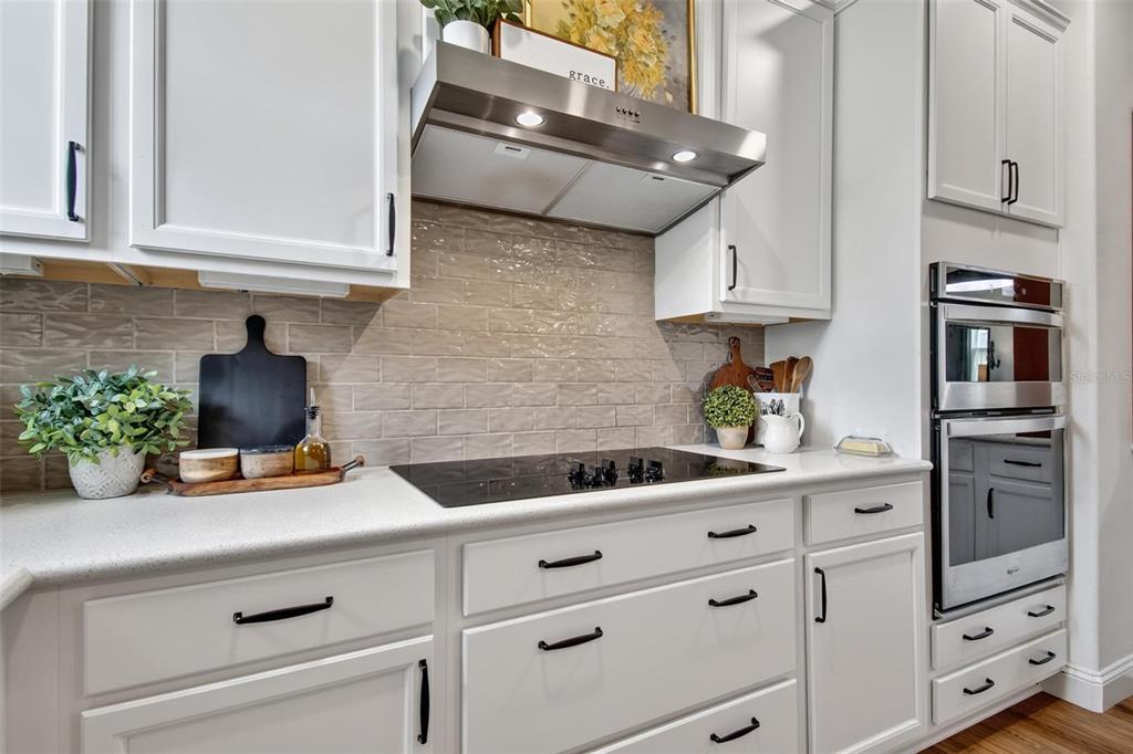 A kitchen features white cabinets, a stainless steel range hood, and a subway tile backsplash — 48 OAKLEAF WAY, PALM COAST, FL