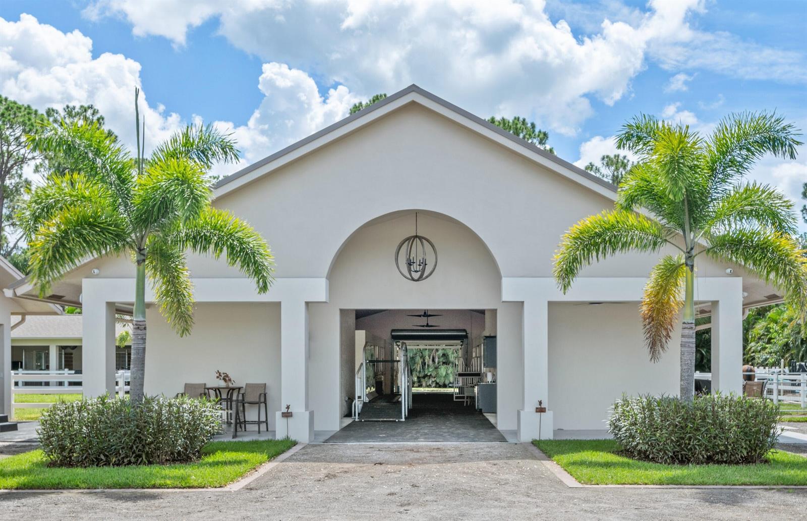 A symmetrical, light-colored building with a central arched breezeway flanked by two palm trees — 1464 Stallion Drive, Loxahatchee FL 33470, LOXAHATCHEE, FL