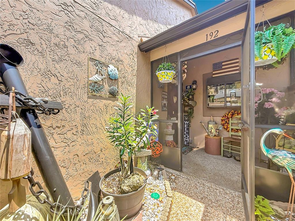 A white front door with a floral basket hangs next to a doorway leading into a kitchen — 940 DOUGLAS AVENUE UNIT 192, ALTAMONTE SPRINGS, FL