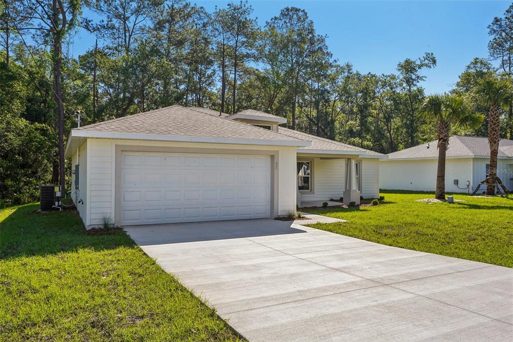 A single-story house with a white garage, light siding, and a concrete driveway — 8973 N TROJAN DRIVE, CITRUS SPRINGS, FL