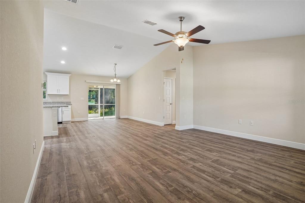 An open-concept living and dining area features wood-look flooring, vaulted ceilings, and a kitchen — 8973 N TROJAN DRIVE, CITRUS SPRINGS, FL