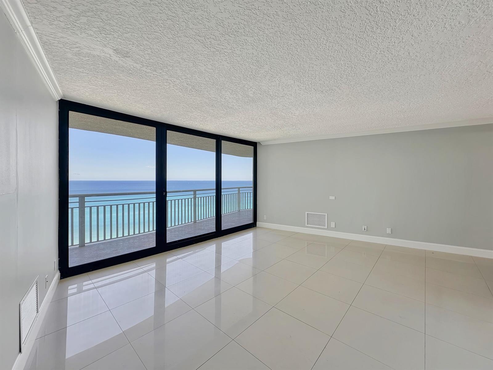 An empty room features large sliding glass doors overlooking the ocean and light-colored tile flooring — 3000 N Ocean Drive, Singer Island FL 33404, SINGER ISLAND, FL