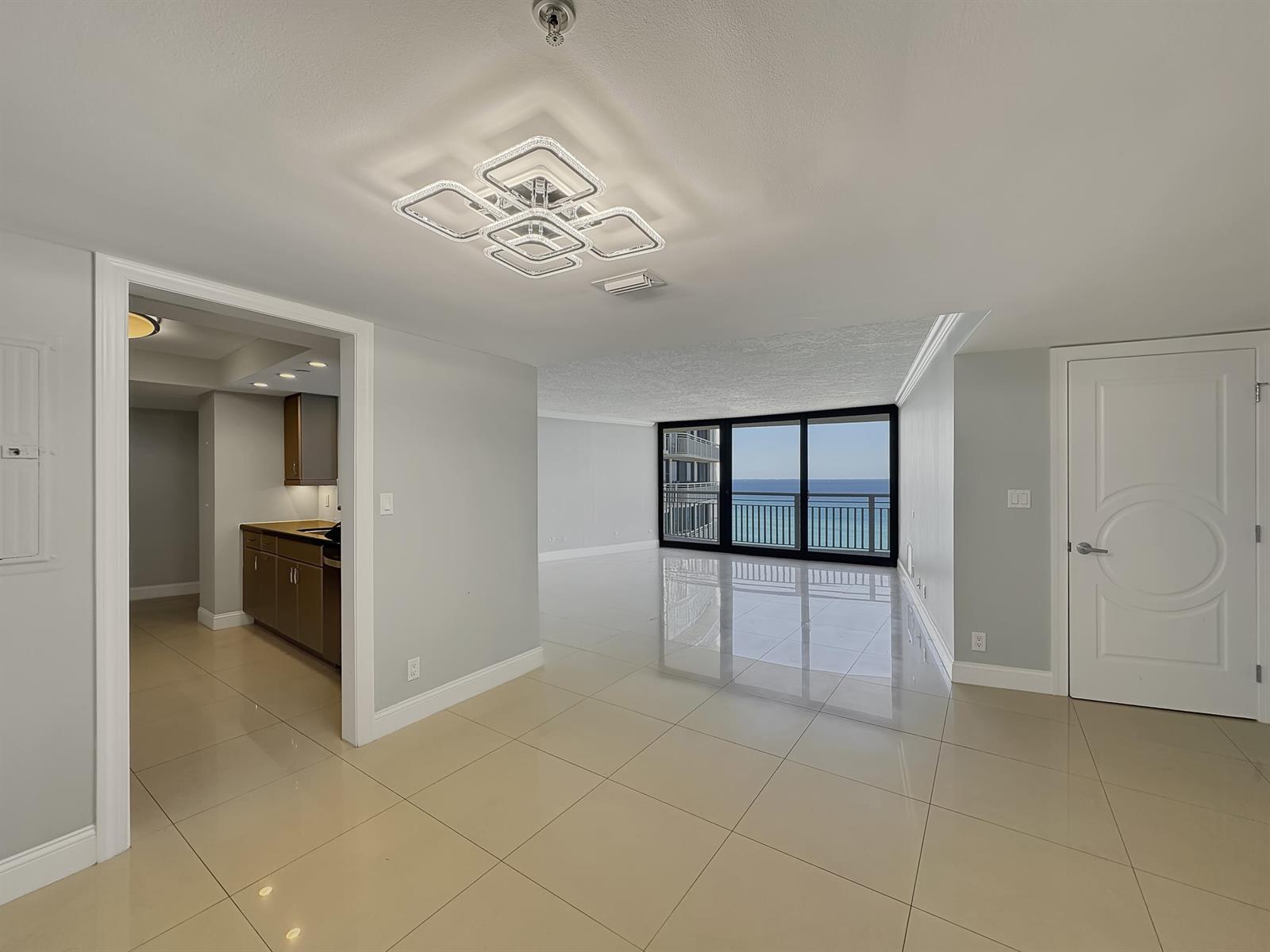 An open-concept living area with tile flooring, a modern light fixture, and ocean views — 3000 N Ocean Drive, Singer Island FL 33404, SINGER ISLAND, FL
