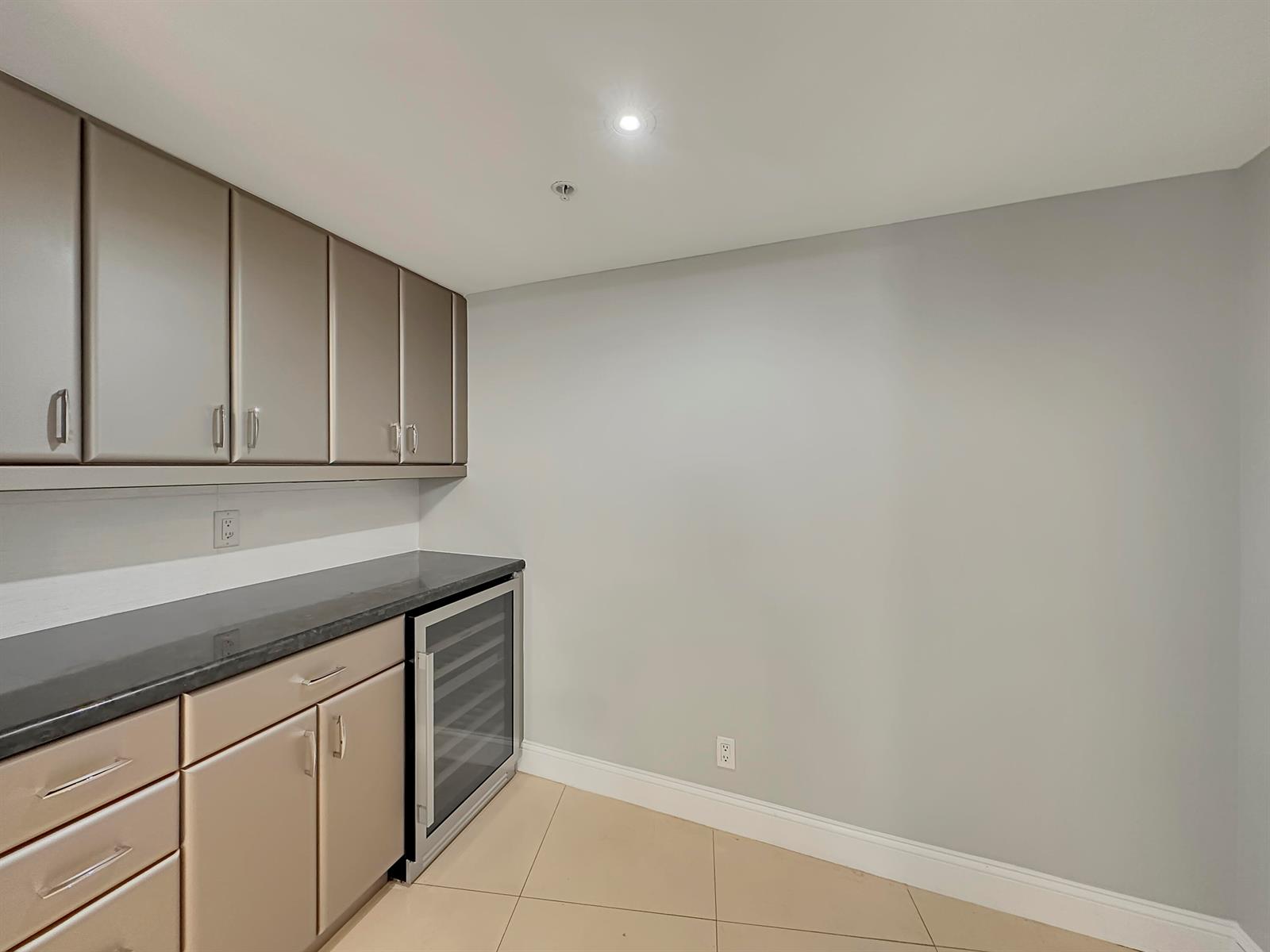 A wet bar area features metallic cabinets, a black countertop, and a built-in wine cooler — 3000 N Ocean Drive, Singer Island FL 33404, SINGER ISLAND, FL