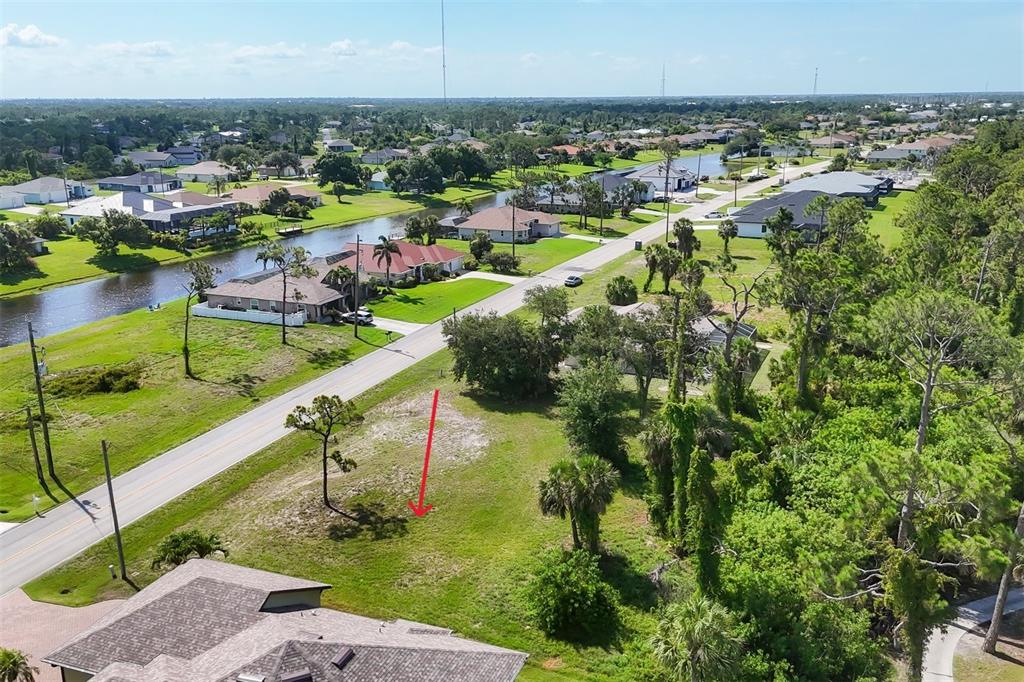 An aerial view shows a vacant, grassy residential lot next to a road and canal — 760 ROTONDA CIRCLE, ROTONDA WEST, FL