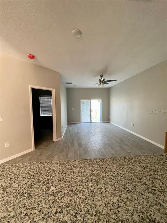 A view from a granite countertop looking into an open-concept living area with tile flooring — 407 BEDLINGTON COURT, KISSIMMEE, FL