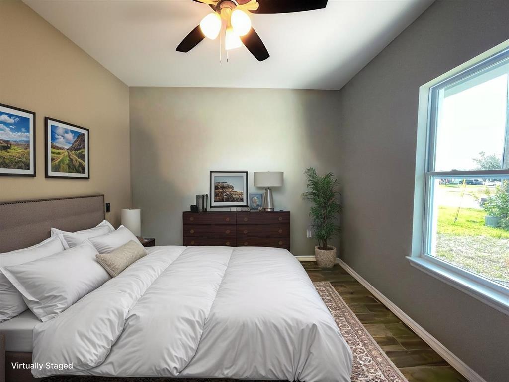 A bedroom with a bed, dresser, ceiling fan, and a window overlooking a grassy area — 407 BEDLINGTON COURT, KISSIMMEE, FL
