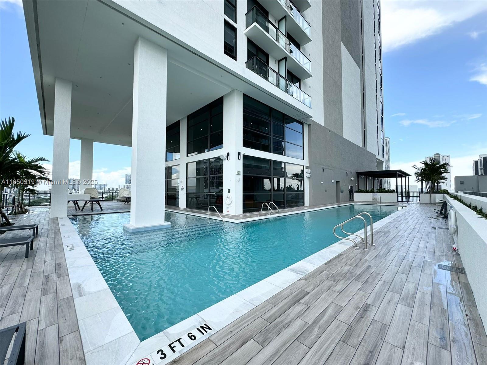 A swimming pool with a depth marker sits on a deck beneath a modern building — 1642 NE 1st Ave # 2409, Miami FL 33132, MIAMI, FL
