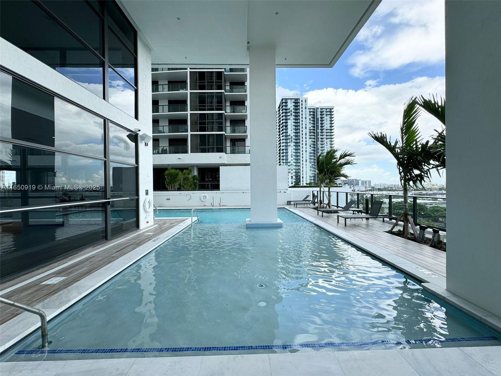 An outdoor swimming pool features a central support pillar and adjacent lounge chairs on a deck — 1642 NE 1st Ave # 2409, Miami FL 33132, MIAMI, FL