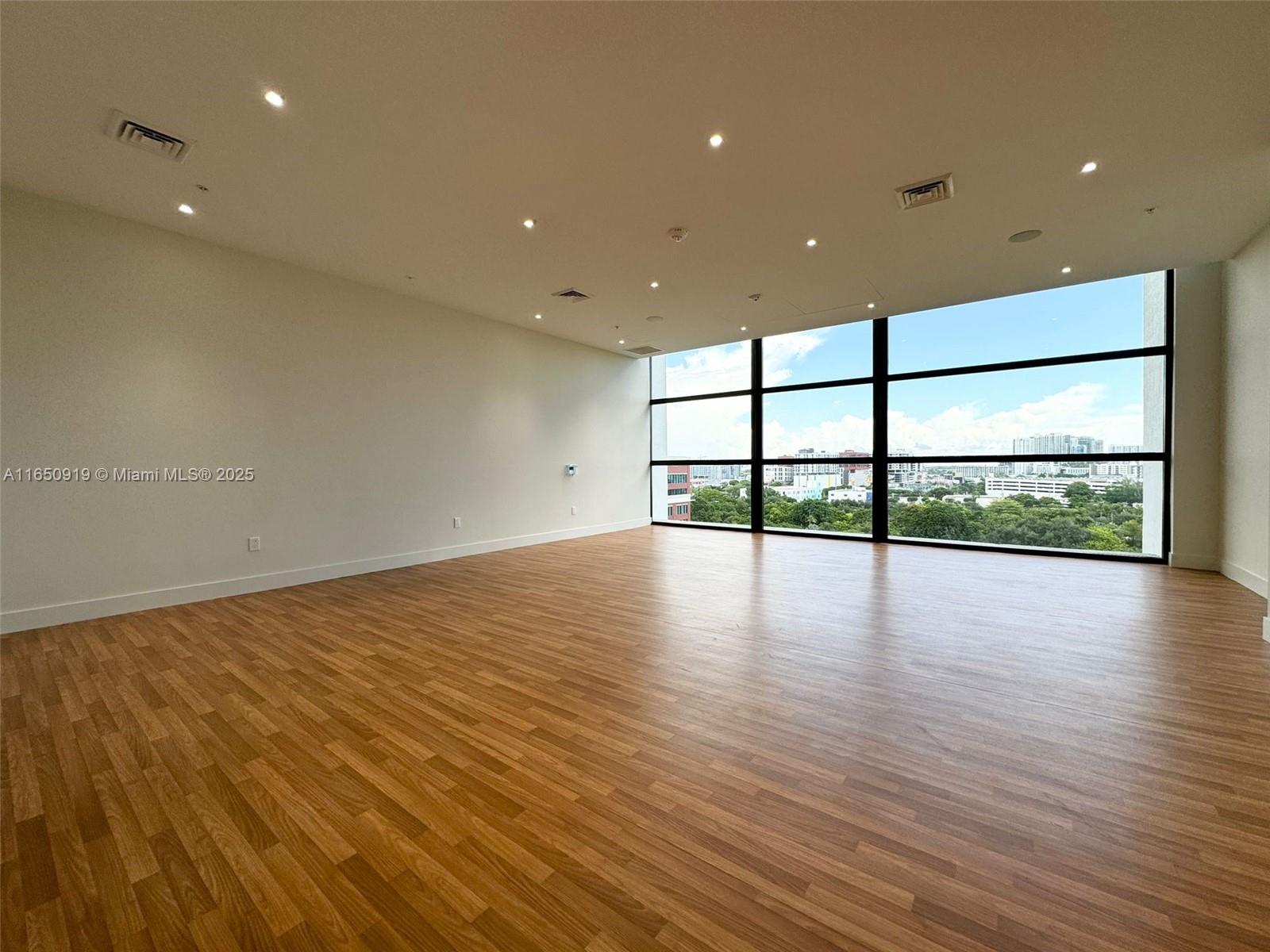 An empty room features light wood-look flooring, recessed ceiling lights, and large floor-to-ceiling windows — 1642 NE 1st Ave # 2409, Miami FL 33132, MIAMI, FL