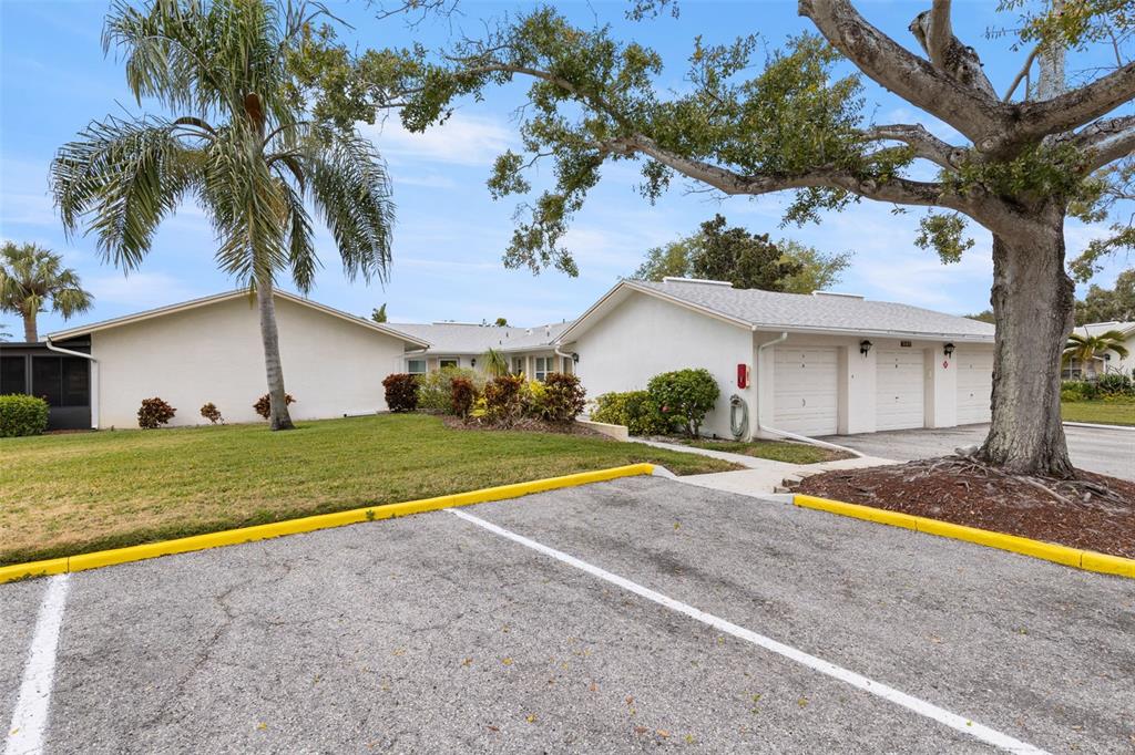 A single-story building with white walls, a gray roof, and attached garages faces a parking lot — 3143 37TH LANE S UNIT B, ST PETERSBURG, FL