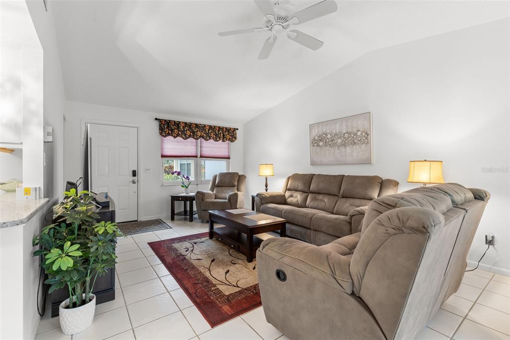 A living room features a beige sofa, a recliner, a coffee table, and tile flooring — 3143 37TH LANE S UNIT B, ST PETERSBURG, FL