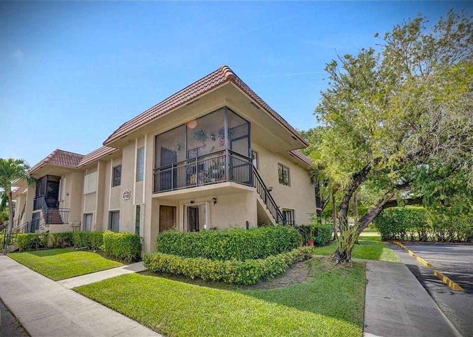 A two-story tan apartment building with a screened balcony and surrounding landscaping — 334 Lakeview Drive # 204, Weston FL 33326, WESTON, FL