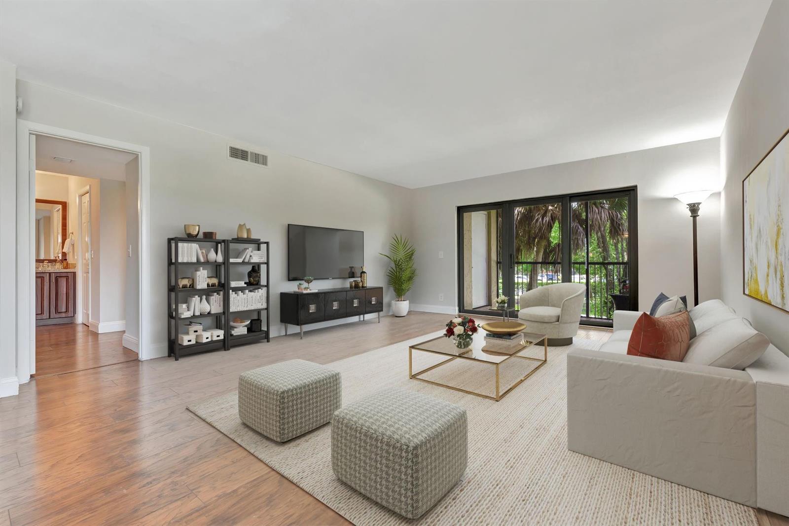 A bright living and dining room features white furniture, a glass coffee table, and wood flooring — 334 Lakeview Drive # 204, Weston FL 33326, WESTON, FL