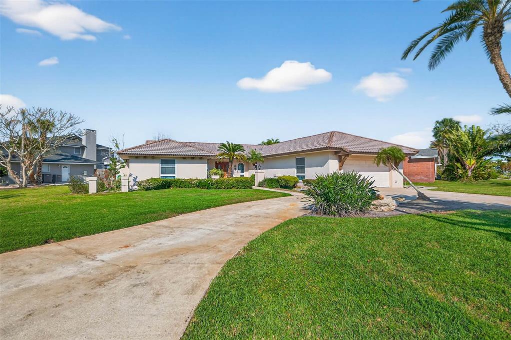 A single-story house with a tiled roof, concrete driveway, and palm trees on a lawn — 3103 WEDGEWOOD DRIVE, BELLEAIR BEACH, FL