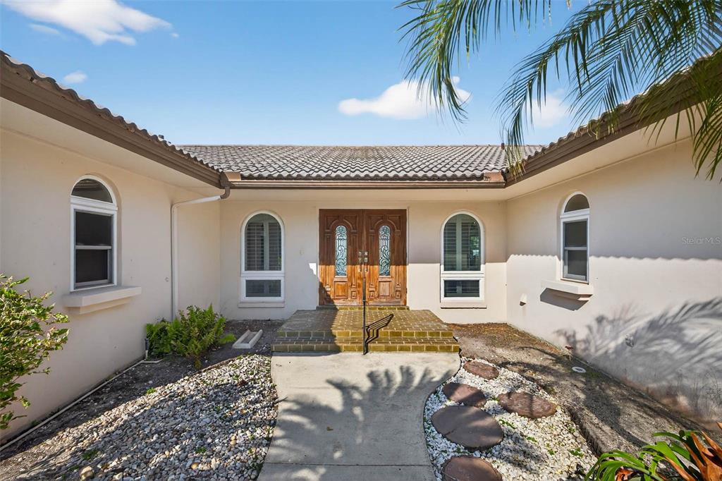 A view of a house exterior featuring a double front door and arched windows — 3103 WEDGEWOOD DRIVE, BELLEAIR BEACH, FL