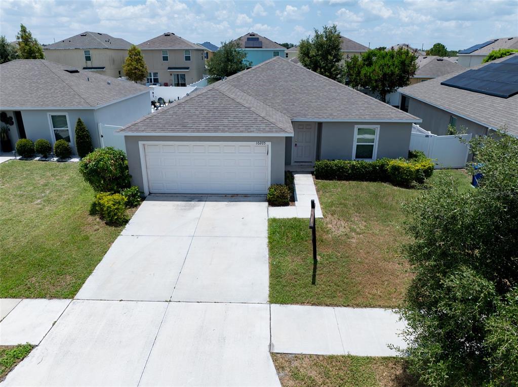 An aerial view of a single-story suburban house with a gray roof and driveway — 10205 CARP HOLLOW ROAD, SUN CITY CENTER, FL