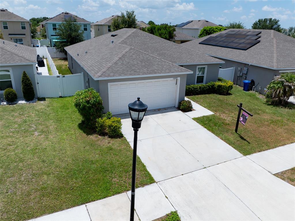 An aerial view shows a single-story house with a two-car garage and a driveway — 10205 CARP HOLLOW ROAD, SUN CITY CENTER, FL