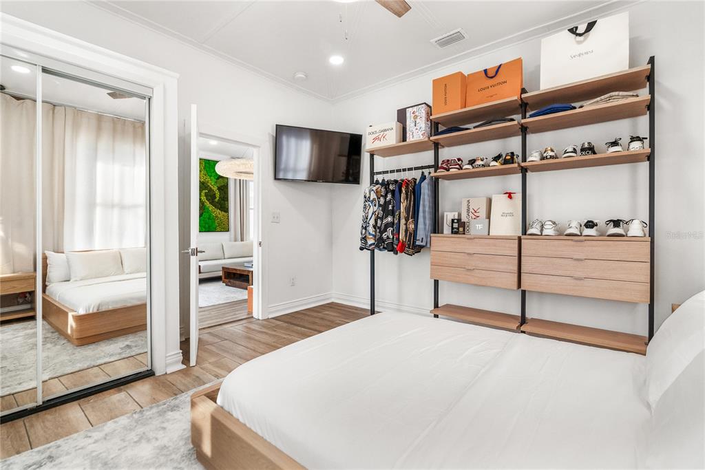 A bedroom features a bed, a mirrored closet, and an open shelving unit for clothing — 3513 N 15TH STREET, TAMPA, FL