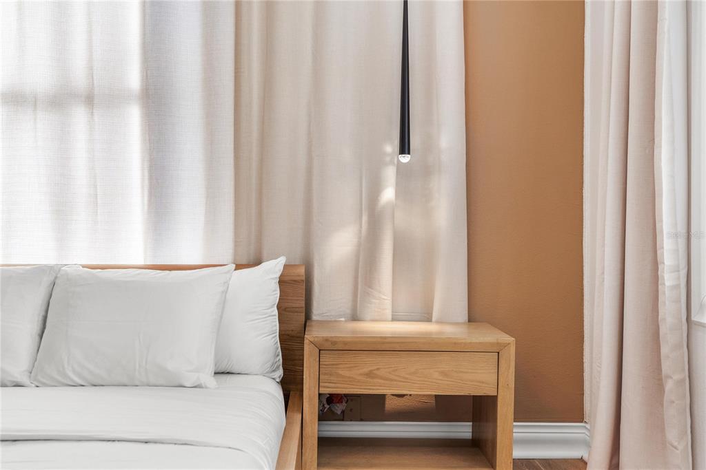 A bedroom features a wooden bed frame, a matching nightstand, and a hanging pendant light — 3513 N 15TH STREET, TAMPA, FL