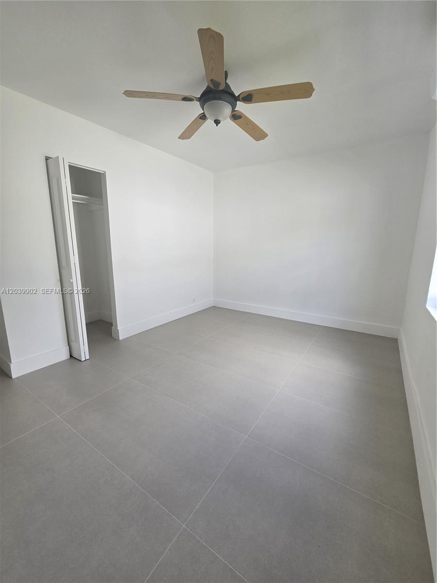An empty bedroom features white walls, large gray floor tiles, and a ceiling fan — 237 SW 13th St # 4, Dania Beach FL 33004, DANIA BEACH, FL
