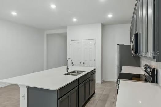 A modern kitchen features a white island with a sink, grey cabinets, and stainless steel appliances — 7043 TWILIGHT BAY DRIVE, WINTER GARDEN, FL