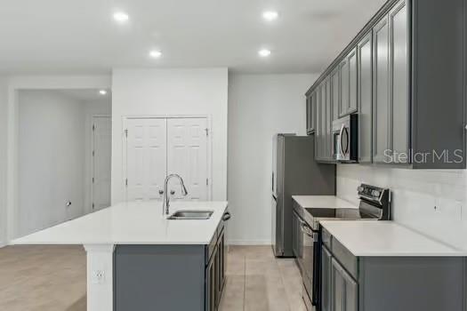 A kitchen features dark gray cabinets, white countertops, a center island, and stainless steel appliances — 7043 TWILIGHT BAY DRIVE, WINTER GARDEN, FL