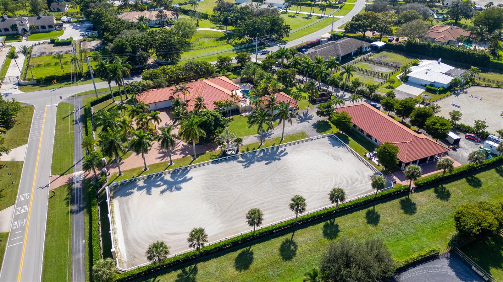 An aerial view shows a residential property with a large riding arena and stables — 14943 Paddock Drive, Wellington FL 33414, WELLINGTON, FL