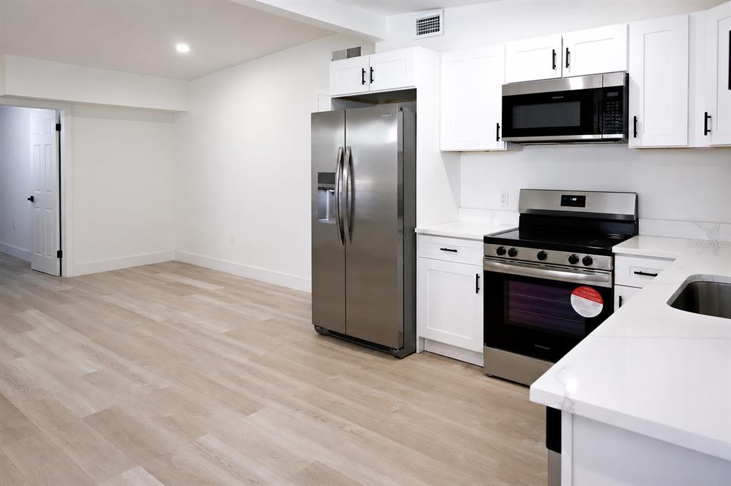 A kitchen with white cabinets, stainless steel appliances, and light wood-look flooring — 9001 82ND STREET, SEMINOLE, FL
