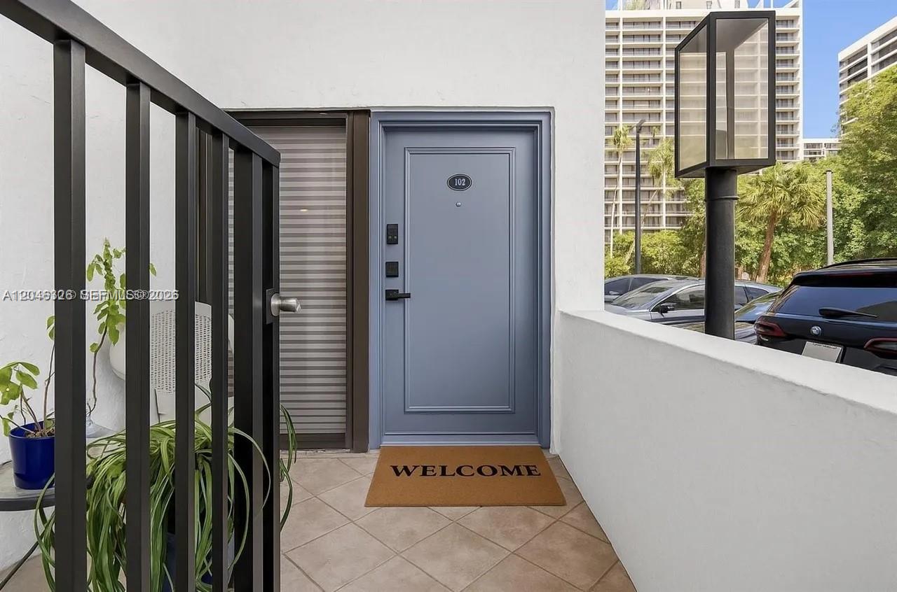 A blue front door with a welcome mat sits at the entrance of a residence — 2715 Tigertail Ave # 102, Miami FL 33133, MIAMI, FL