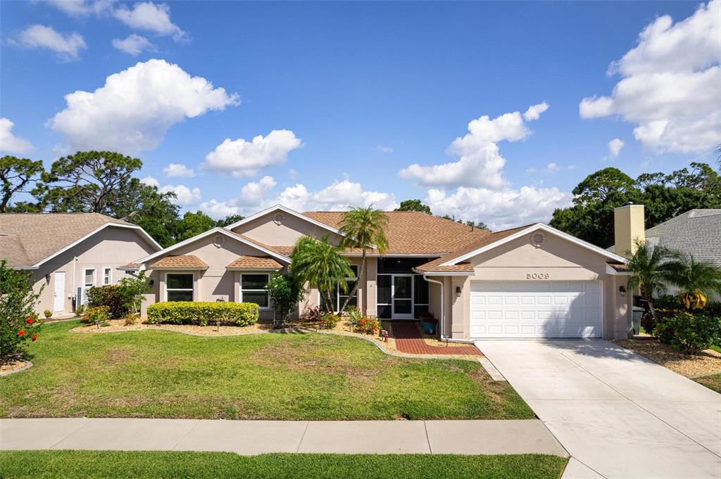 A single-story suburban house with a beige exterior, a two-car garage, and a landscaped lawn — 5009 SOUTHERN PINE CIRCLE, VENICE, FL