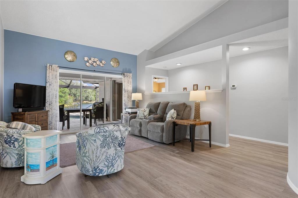 A living room features light wood flooring, a blue accent wall, and a sliding glass door — 5009 SOUTHERN PINE CIRCLE, VENICE, FL