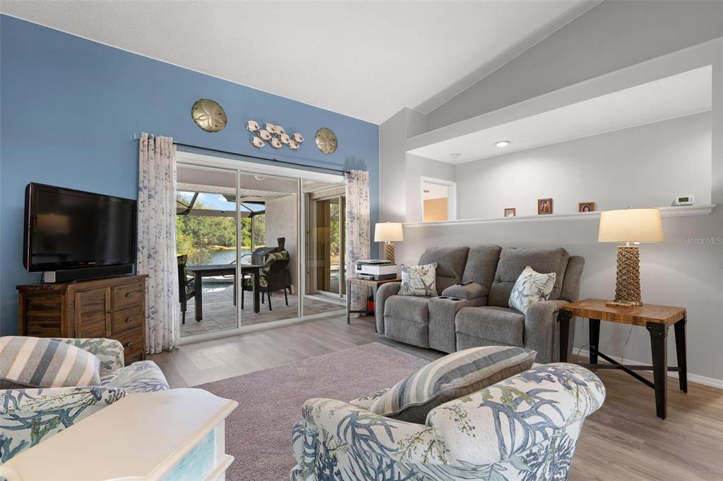 A living room features a blue accent wall, gray sofa, and sliding doors to a patio — 5009 SOUTHERN PINE CIRCLE, VENICE, FL