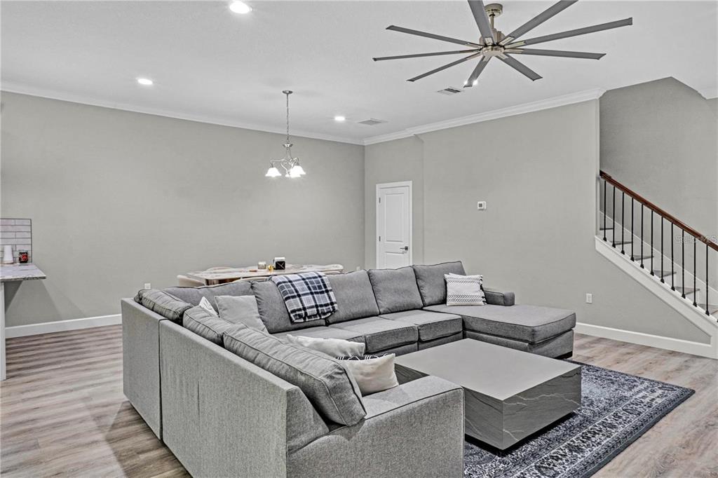 A living room features a large gray sectional sofa, a coffee table, and a staircase — 746 GRAND CYPRESS LANE, TARPON SPRINGS, FL