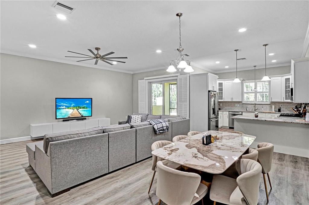 An open-concept living and dining area features a sectional sofa, marble table, and white kitchen — 746 GRAND CYPRESS LANE, TARPON SPRINGS, FL