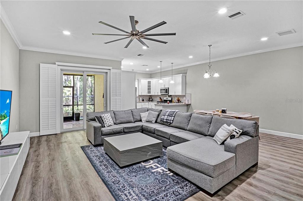 A living room with a large gray sectional sofa, a coffee table, and an open kitchen — 746 GRAND CYPRESS LANE, TARPON SPRINGS, FL