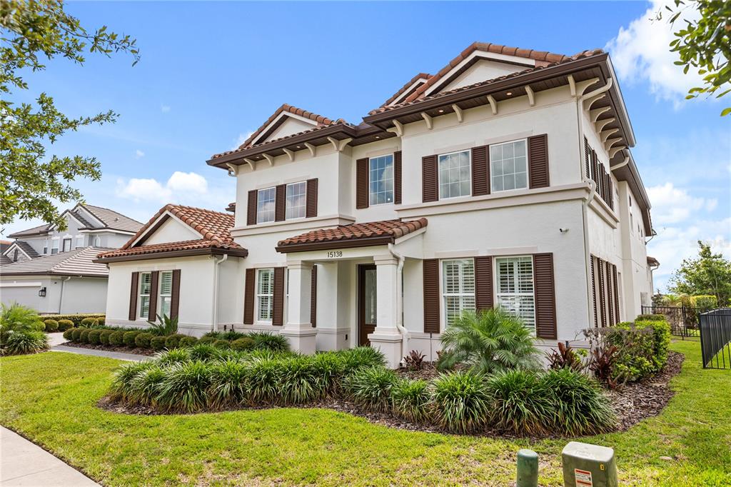 A two-story stucco house with a tile roof and brown shutters sits on a lawn — 15138 SHONAN GOLD DRIVE, WINTER GARDEN, FL