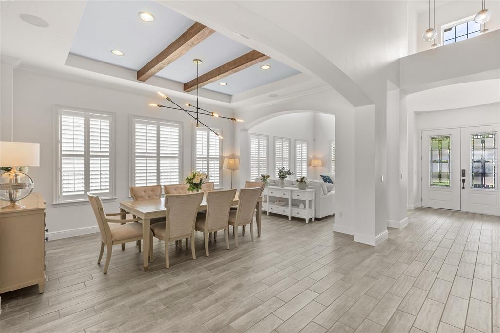 A dining room with a coffered ceiling, wood beams, and light wood-look tile flooring — 15138 SHONAN GOLD DRIVE, WINTER GARDEN, FL
