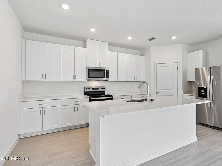A modern kitchen features white cabinets, stainless steel appliances, and a large central island — 59 ARARAT DRIVE, PALM COAST, FL
