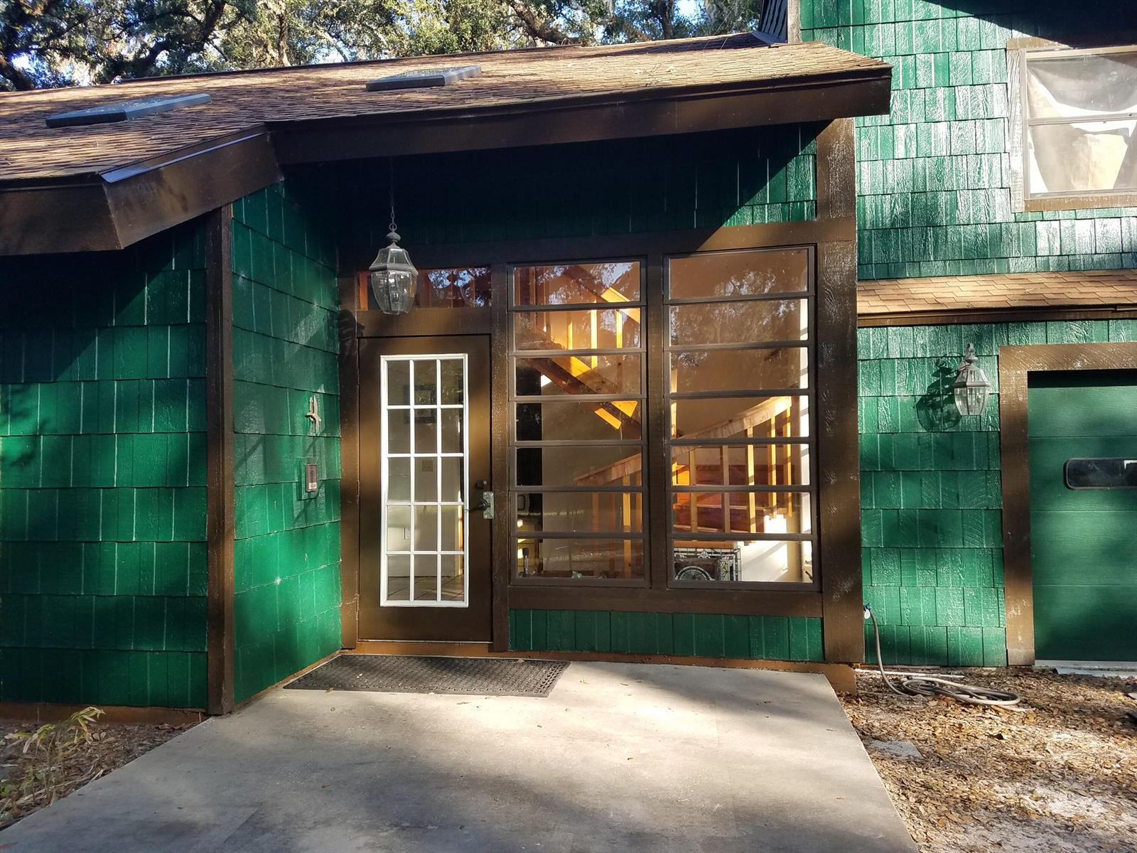 The exterior of a green shingled house features a brown front door and large windows — 1588 Cr 652a, FL 33513, FL