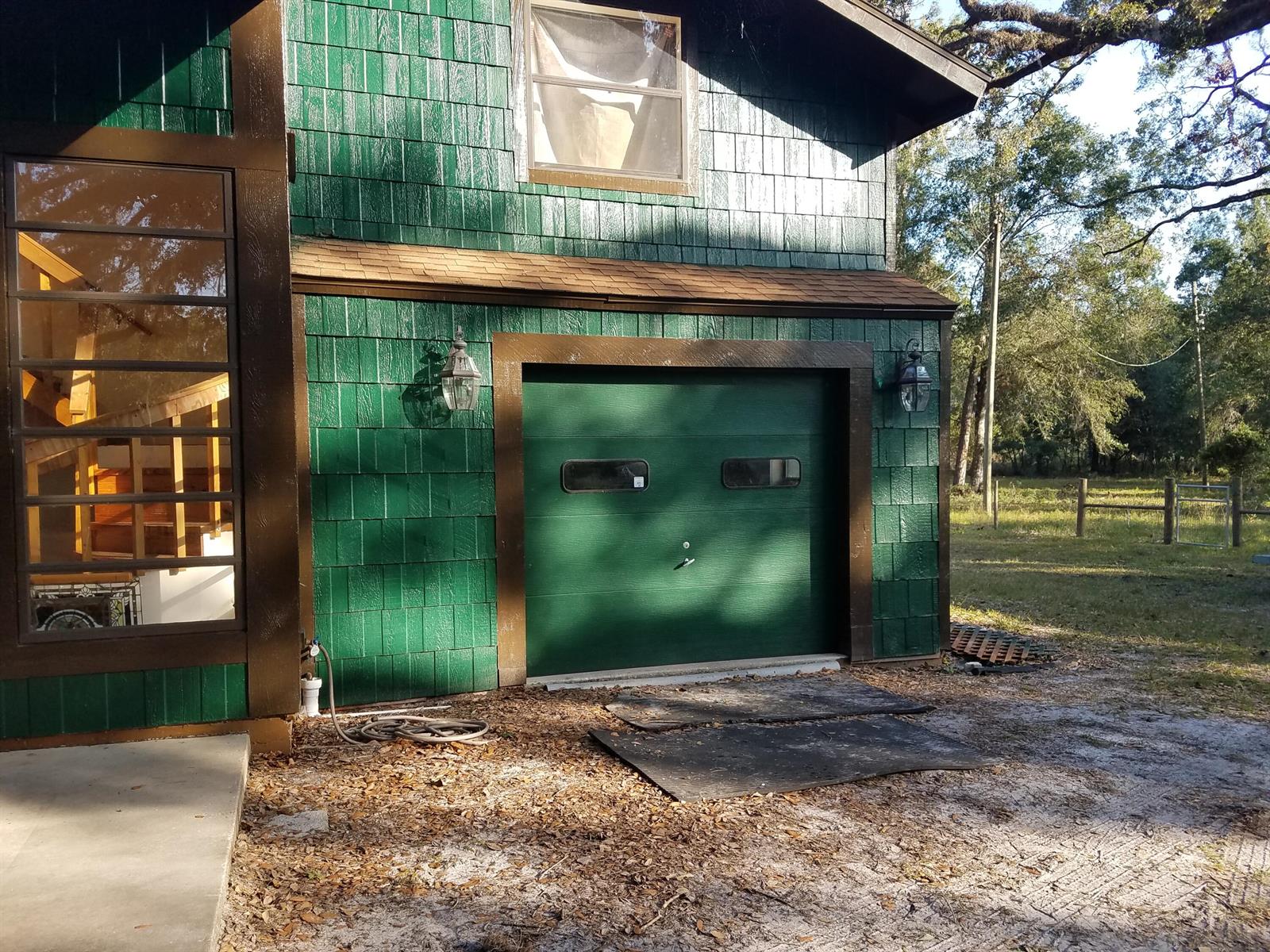 A green shingled building features a single-car garage door with two small windows — 1588 Cr 652a, FL 33513, FL