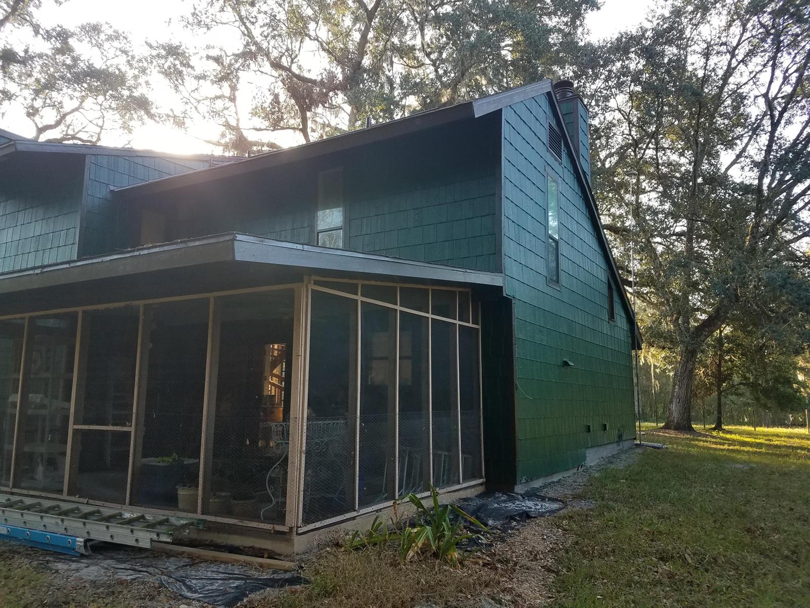 A green-sided house with a screened-in porch and a metal ladder on the ground — 1588 Cr 652a, FL 33513, FL