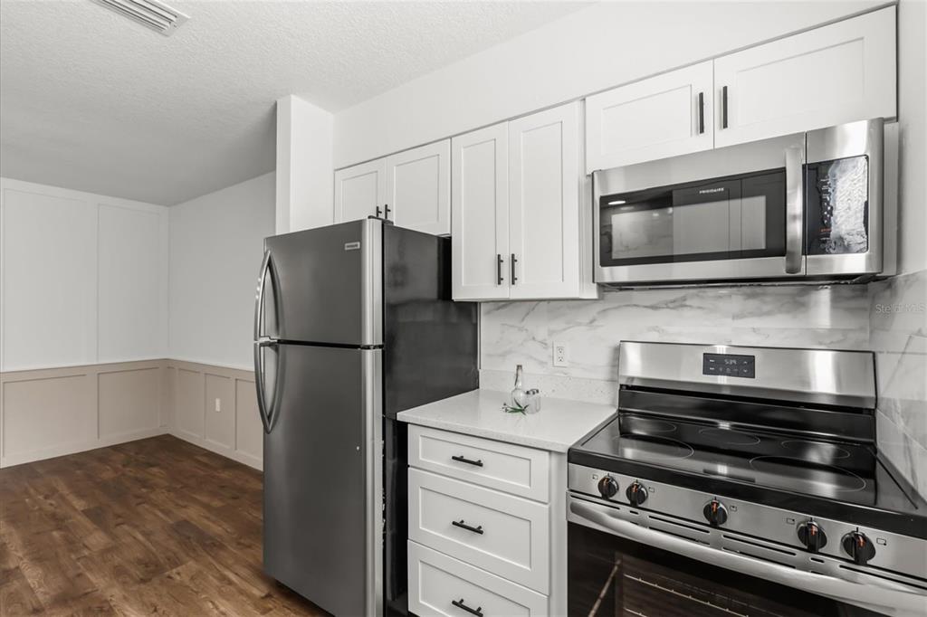 A kitchen features white cabinets, stainless steel appliances, and a marble-patterned backsplash — 22632 SE HAWTHORNE ROAD, HAWTHORNE, FL