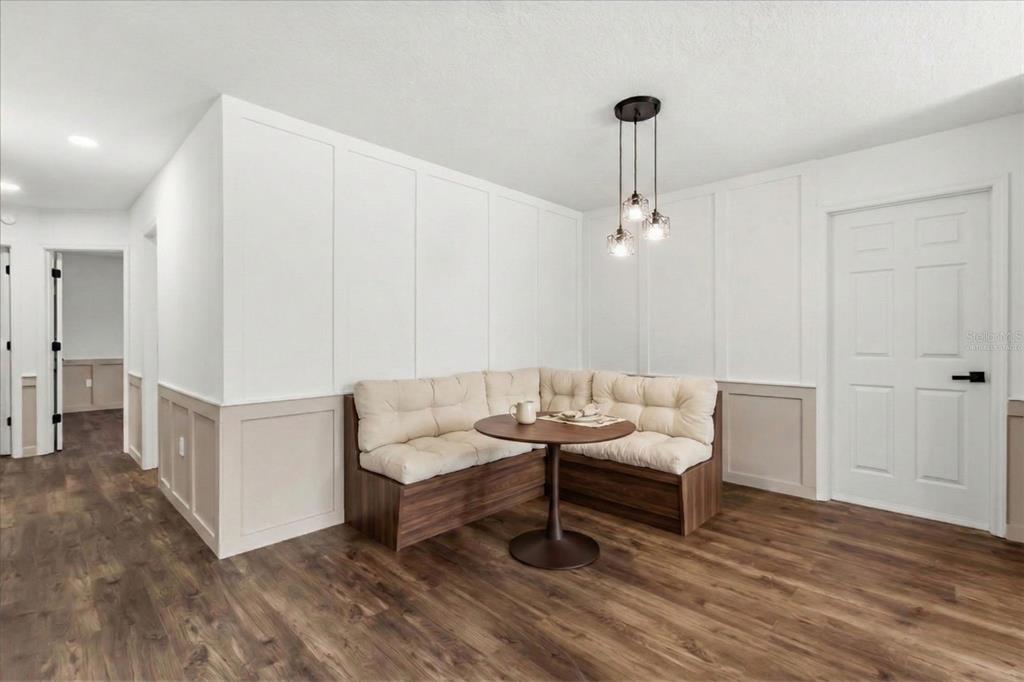 A dining nook features a corner bench, a round table, and white board-and-batten wall paneling — 22632 SE HAWTHORNE ROAD, HAWTHORNE, FL