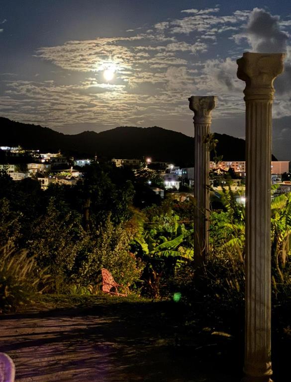 A night view of a town from a terrace with two classical columns and chairs — 114 ROUTE 901 UNIT KM 2.0, MAUNABO, PR