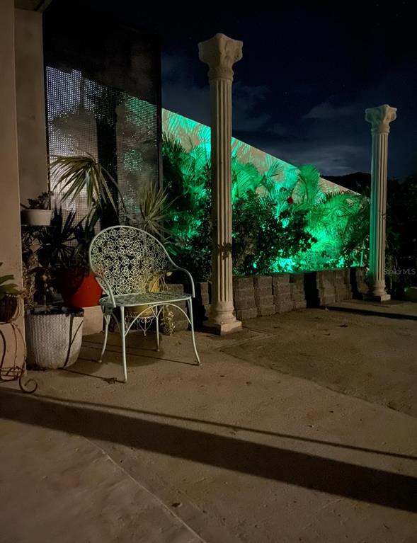 A patio at night features a metal chair, two decorative columns, and green landscape lighting — 114 ROUTE 901 UNIT KM 2.0, MAUNABO, PR