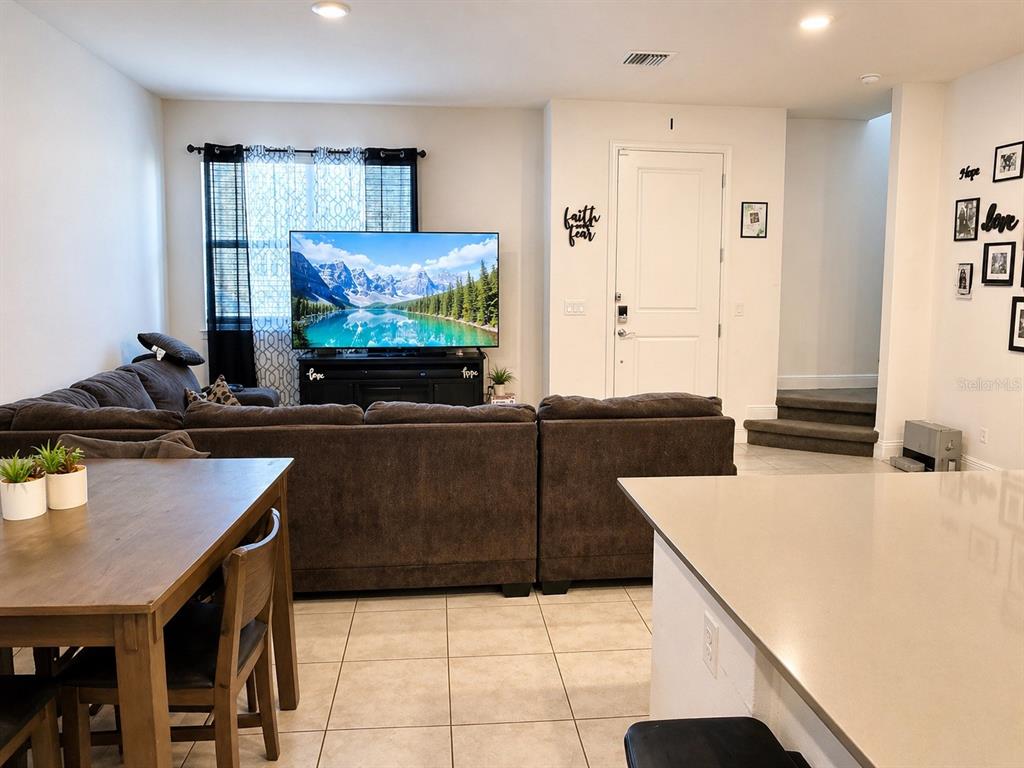 A living room features a large sectional sofa, a television on a stand, and tile flooring — 3890 KNOTTY PINE STREET, ST CLOUD, FL