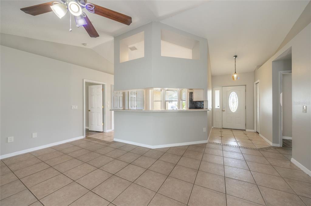 A living area with tile floors, a ceiling fan, and a central kitchen pass-through wall — 37 ROCKEFELLER DRIVE, PALM COAST, FL