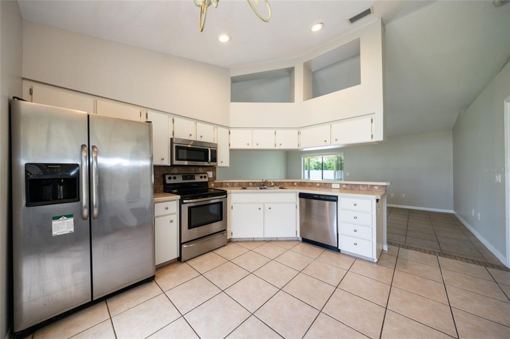 A kitchen with white cabinets, stainless steel appliances, and light-colored tile flooring — 37 ROCKEFELLER DRIVE, PALM COAST, FL